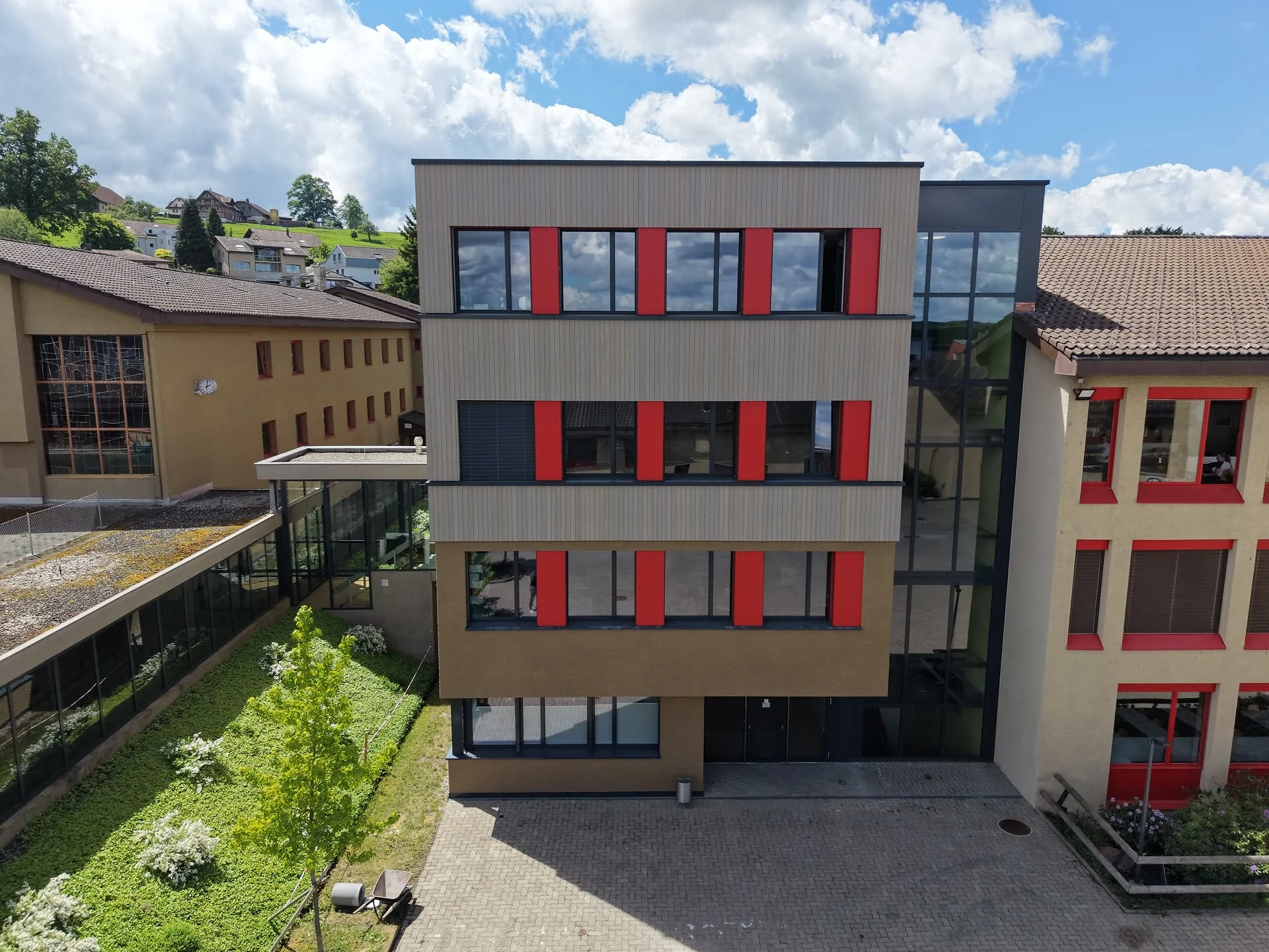 Aufstockung Sekundarschule Sonneweid 2 — Fassade mit Holzverkleidung und roten Storen