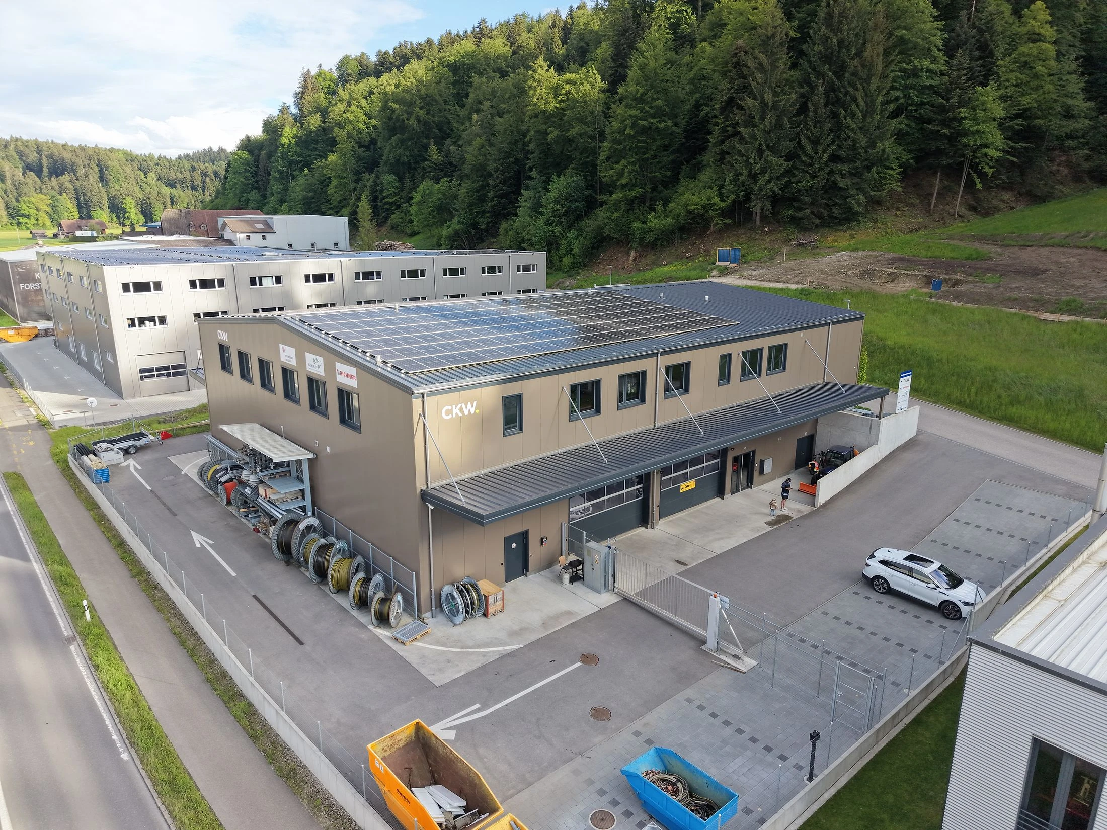 Workspace Willisau — Luftaufnahme: Gewerbehalle am Waldrand im Abendlicht
